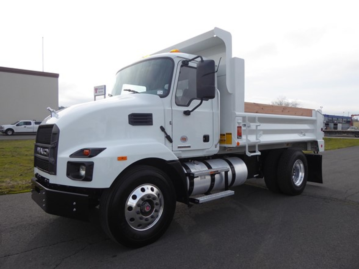 Mack MD6 dump truck from side/front view showing white cab and dump bed with dual rear wheels.