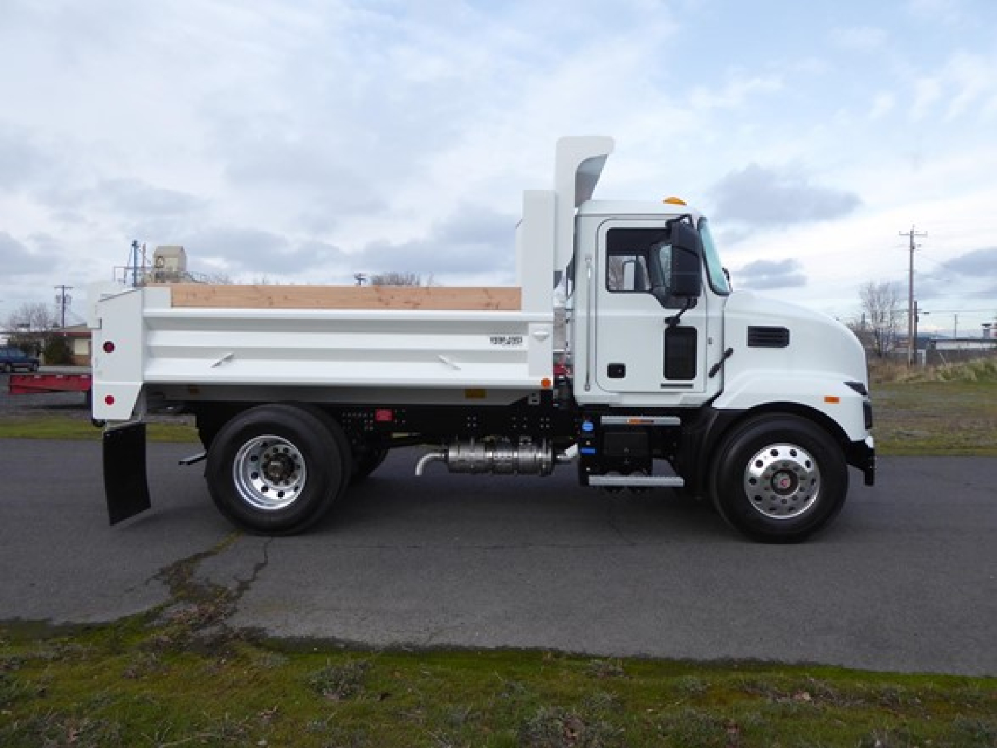 Mack MD6 dump truck side view showing white cab and dump bed with chrome exhaust stack