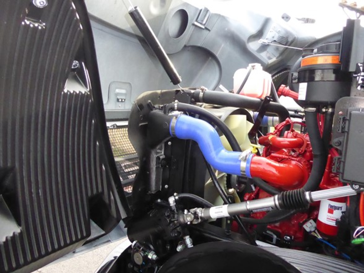 Mack MD6 engine bay with blue hose, red turbocharger, black coolant reservoir, and various hoses and components visible