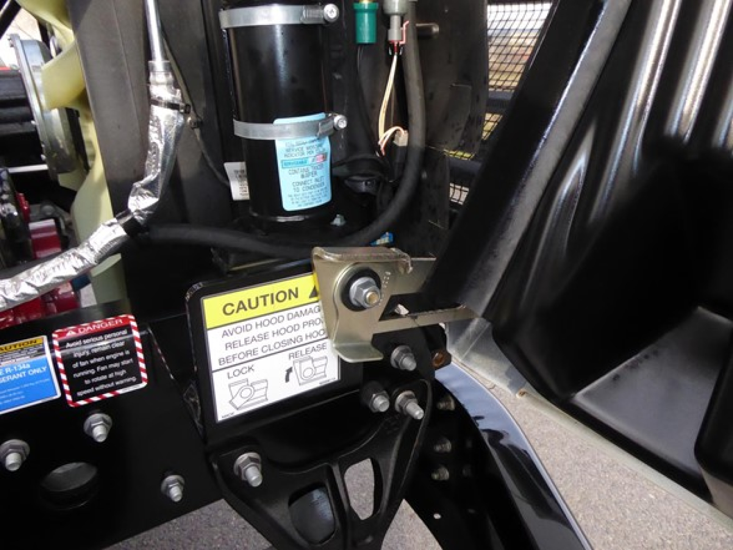 Mack MD6 truck engine bay showing yellow caution label and hydraulic components