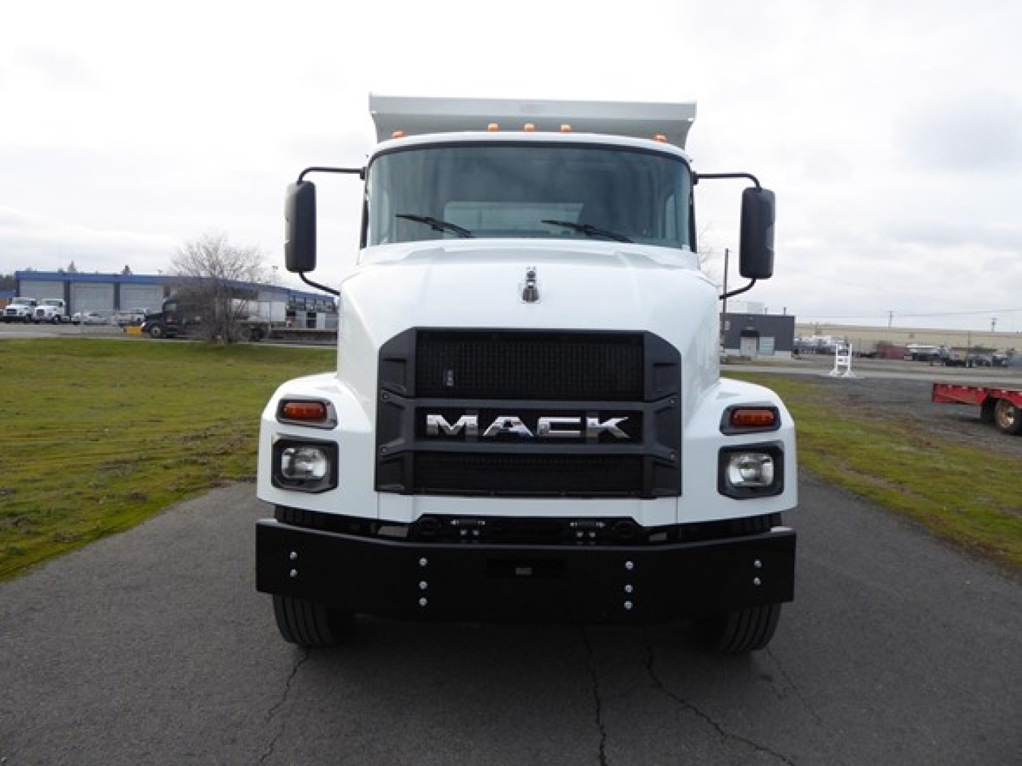 Mack MD6 dump truck front view showing bold grille with MACK lettering and black bumper.