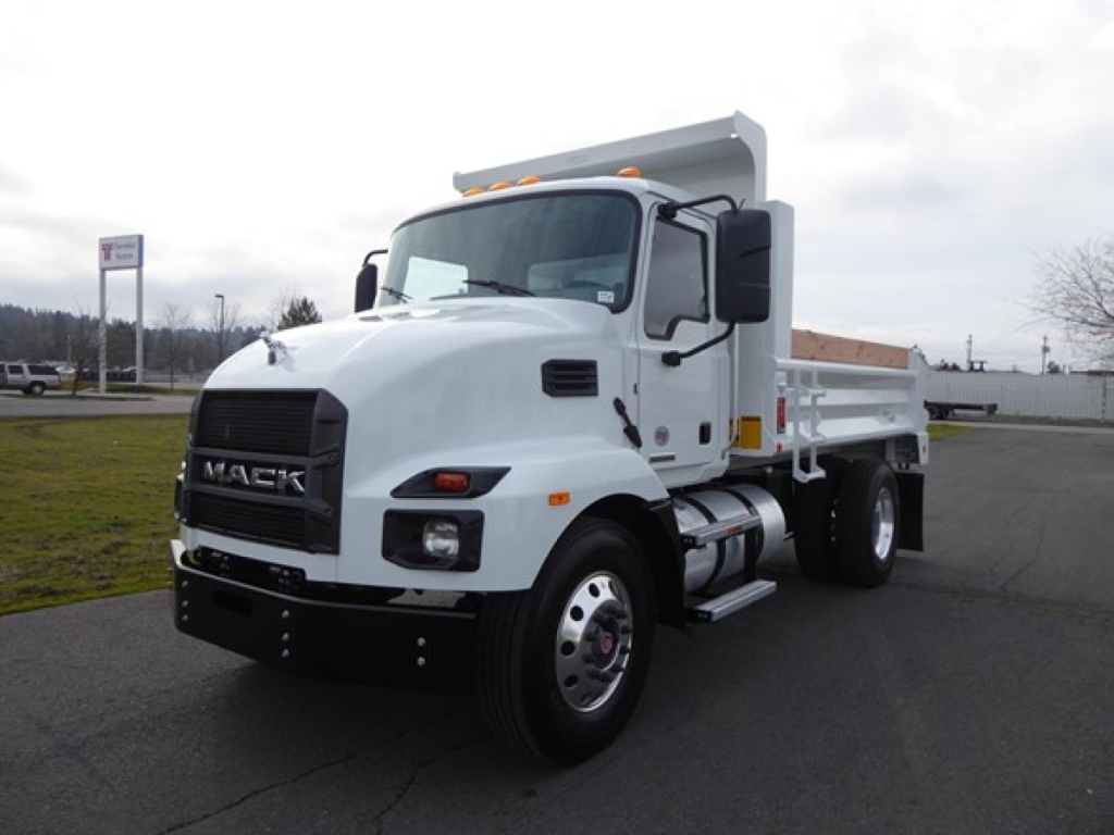 Mack MD6 dump truck in a parking lot, front-left view showing cab and white dump bed.