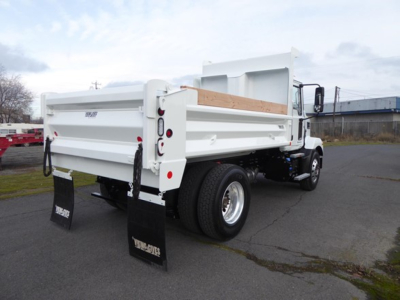 Dump truck rear/side view showing white dump body, dual rear tires, tailgate, and mud flaps with ‘TRU-TRUKS’ branding.