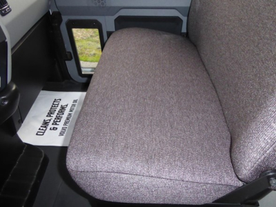 Truck cab interior row seat view of Mack MD6 showing grey fabric seat and door panel.