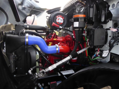 Mack MD6 engine bay showing blue radiator hose, red engine, and various hoses and components.