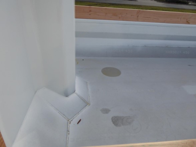 Truck bed surface with white coating showing faint circular footprints and a raised corner seam, view from cabin area.
