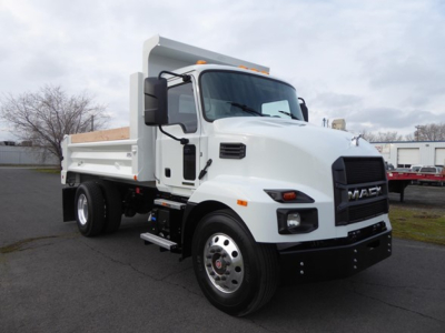 Front-left view of a white 2025 Mack MD6 dump truck showing cab, dump bed, large black grille, and front bumper.