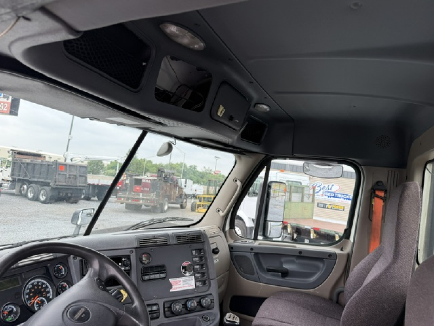 Cab interior of a 2017 Freightliner Cascadia CA125DC showing dash controls and driver seat with windshield view.
