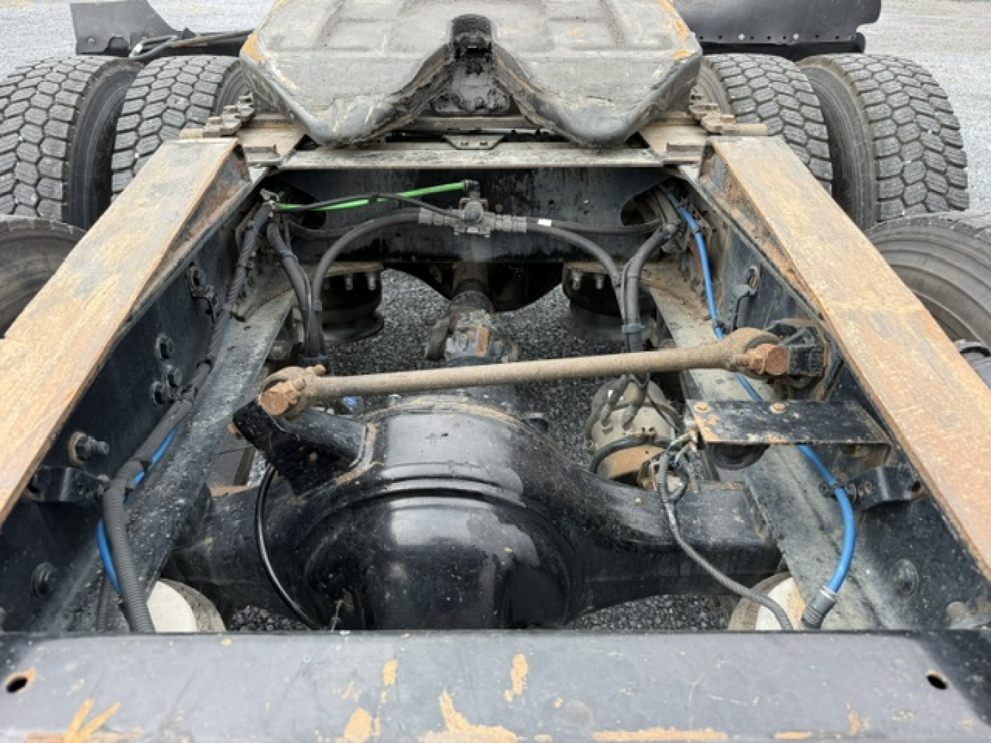Freightliner Cascadia CA125DC rear chassis view showing suspension crossover and drivetrain components with hoses and cables.