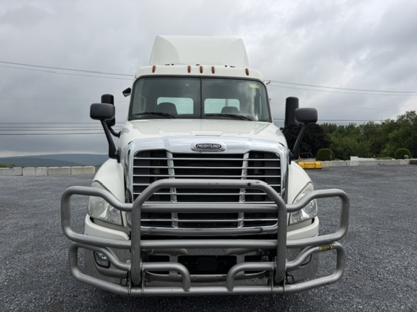 Front view of a white 2017 Freightliner Cascadia CA125DC conventional daycab truck with a metal bull-bar guard on the grille.