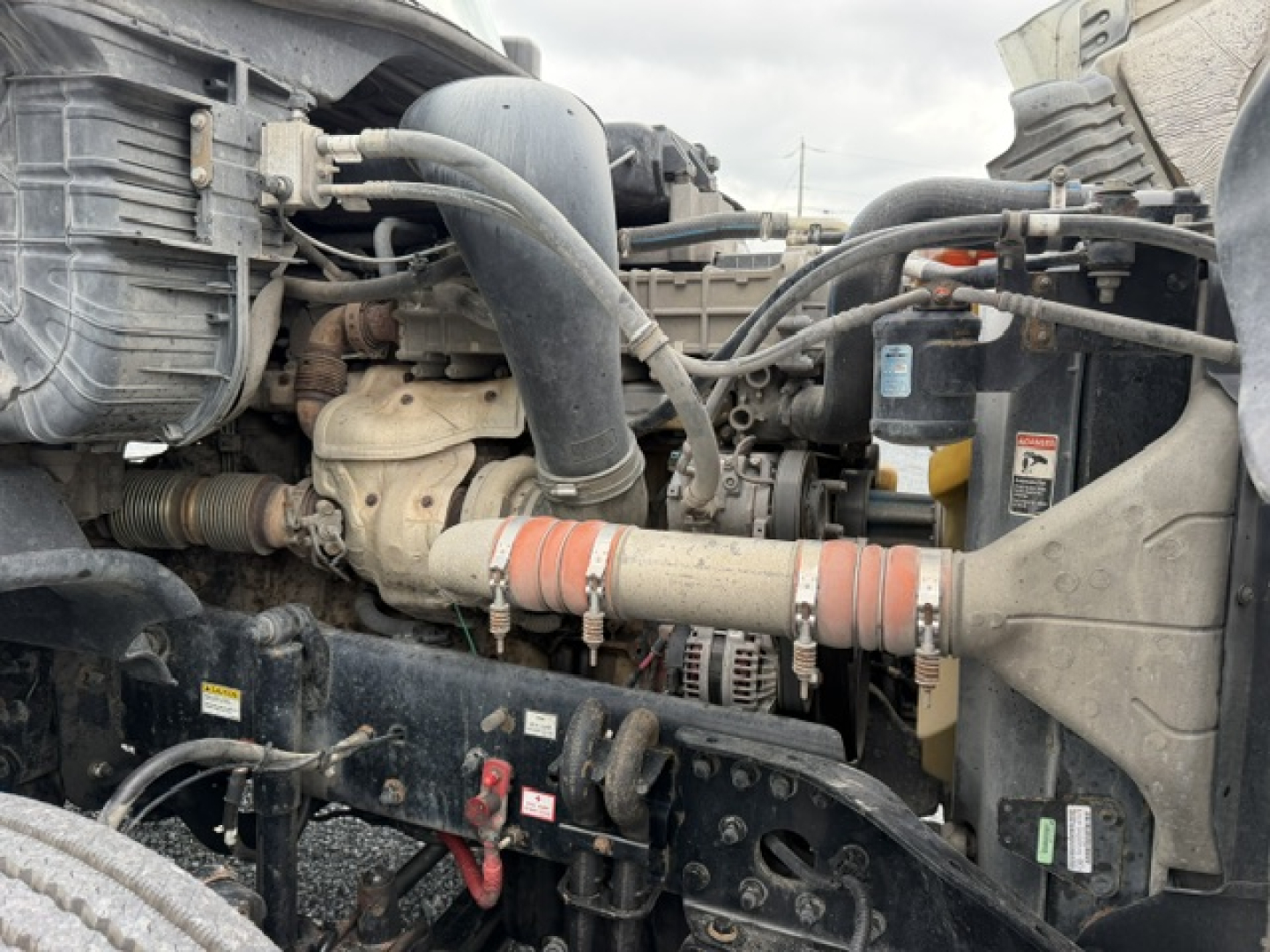 Truck engine bay with hoses, belts, and radiator visible; Turbo/intercooler piping and air intake visible in foreground