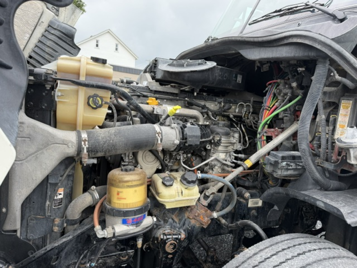 Engine bay of 2017 Freightliner Cascadia CA125DC showing fluid reservoirs and various hoses and wiring.
