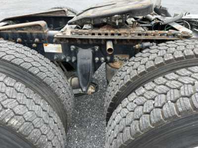 Freightliner Cascadia CA125DC chassis showing dual rear axles and hitch area with tires and frame, view of rear suspension and coupling area.