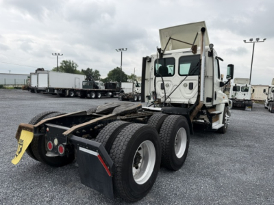 Freightliner Cascadia CA125DC tractor tractor rear view showing fifth wheel area and dual rear axles. Cab visible with mirrors and sleeper top in background.