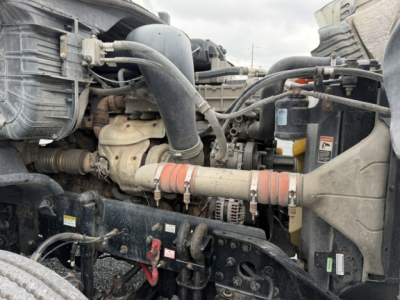 Truck engine bay with hoses, belts, and radiator visible; Turbo/intercooler piping and air intake visible in foreground