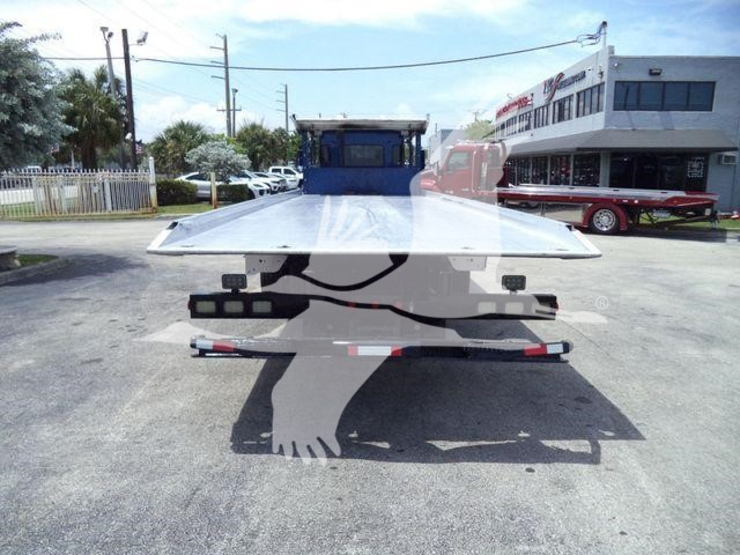 Flatbed tow truck in a lot with a Kenworth T370 rollback. Visible text includes the VIN 2NKHHJ7X6GM483588, stock number T83588, and category/condition details: Rollback, Trucks, Used.