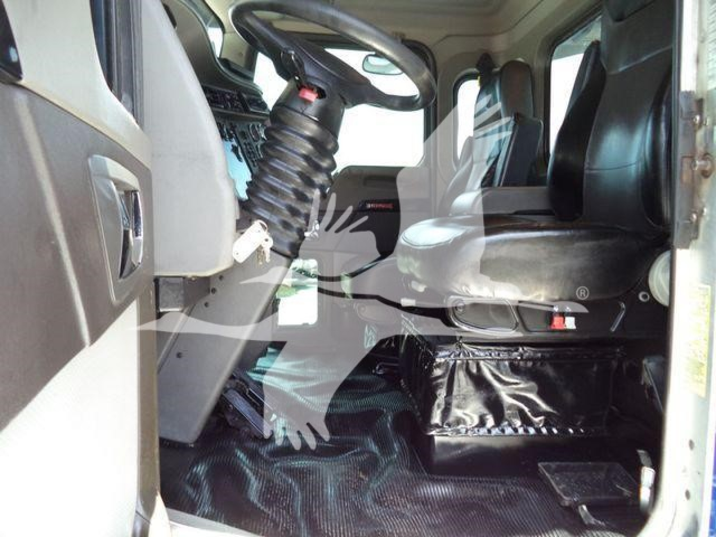 Kenworth T370 truck cab interior showing steering wheel, seat, and dashboard from open door; black floor mat and driver's area visible.