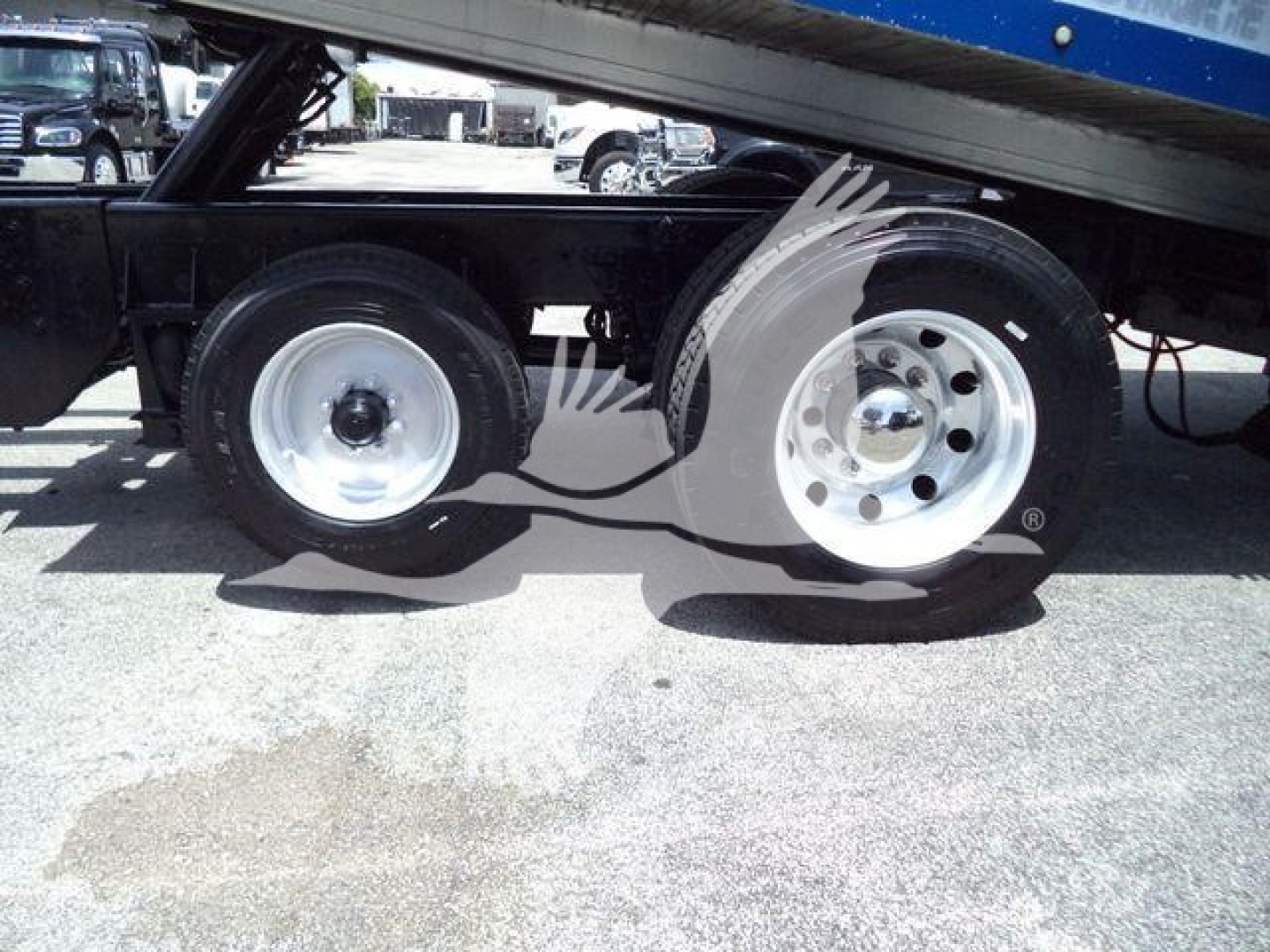 Kenworth T370 rollback trucks showing dual rear axles under the bed with chrome wheels and black undercarriage.