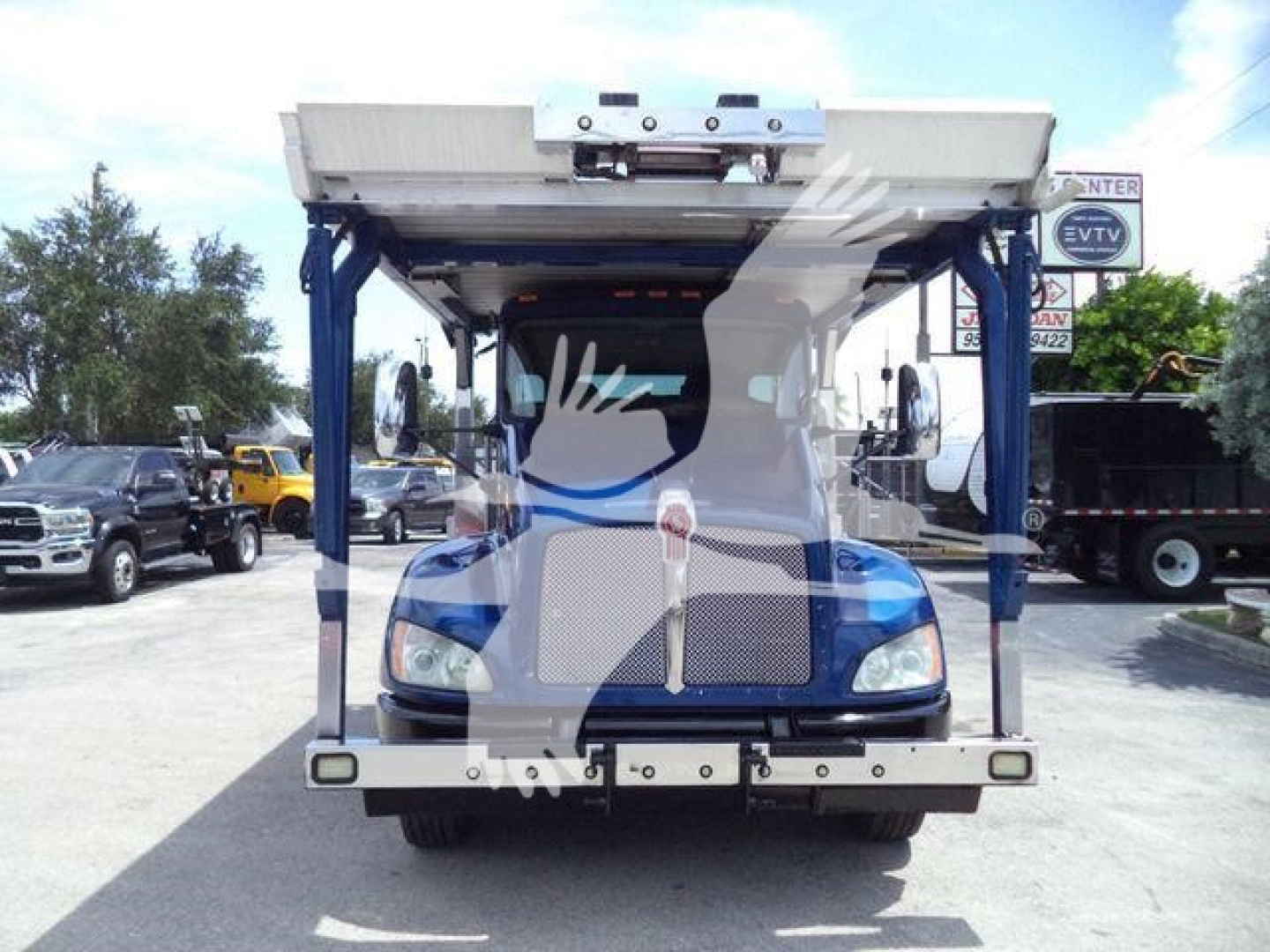 Front view of a 2016 Kenworth T370 rollback truck showing chrome bumper and hydraulic lift bed, blue cab with clear headlights.