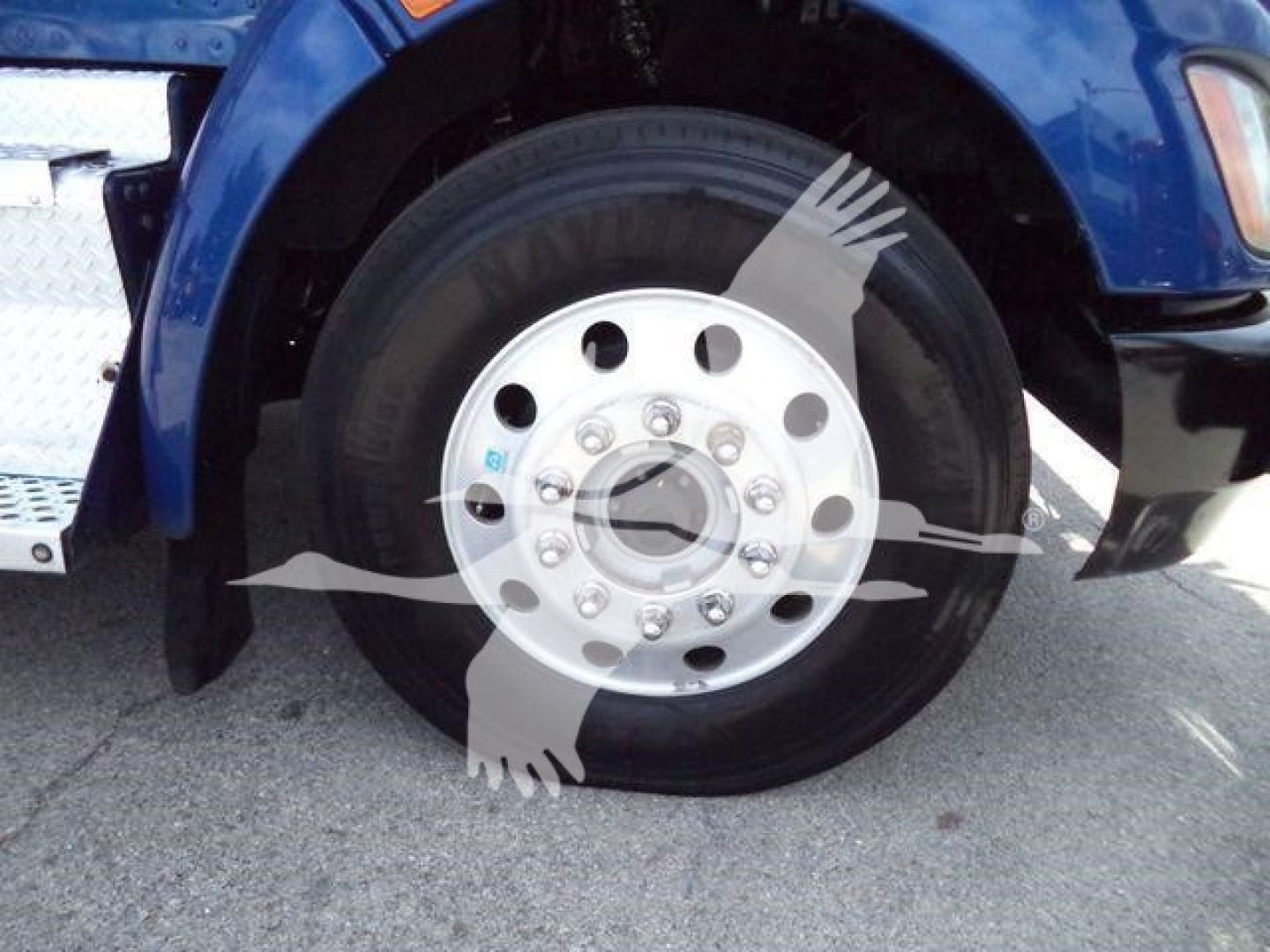 Kenworth T370 wheel and fender close-up showing front tire and polished hubcap with lug nut pattern.