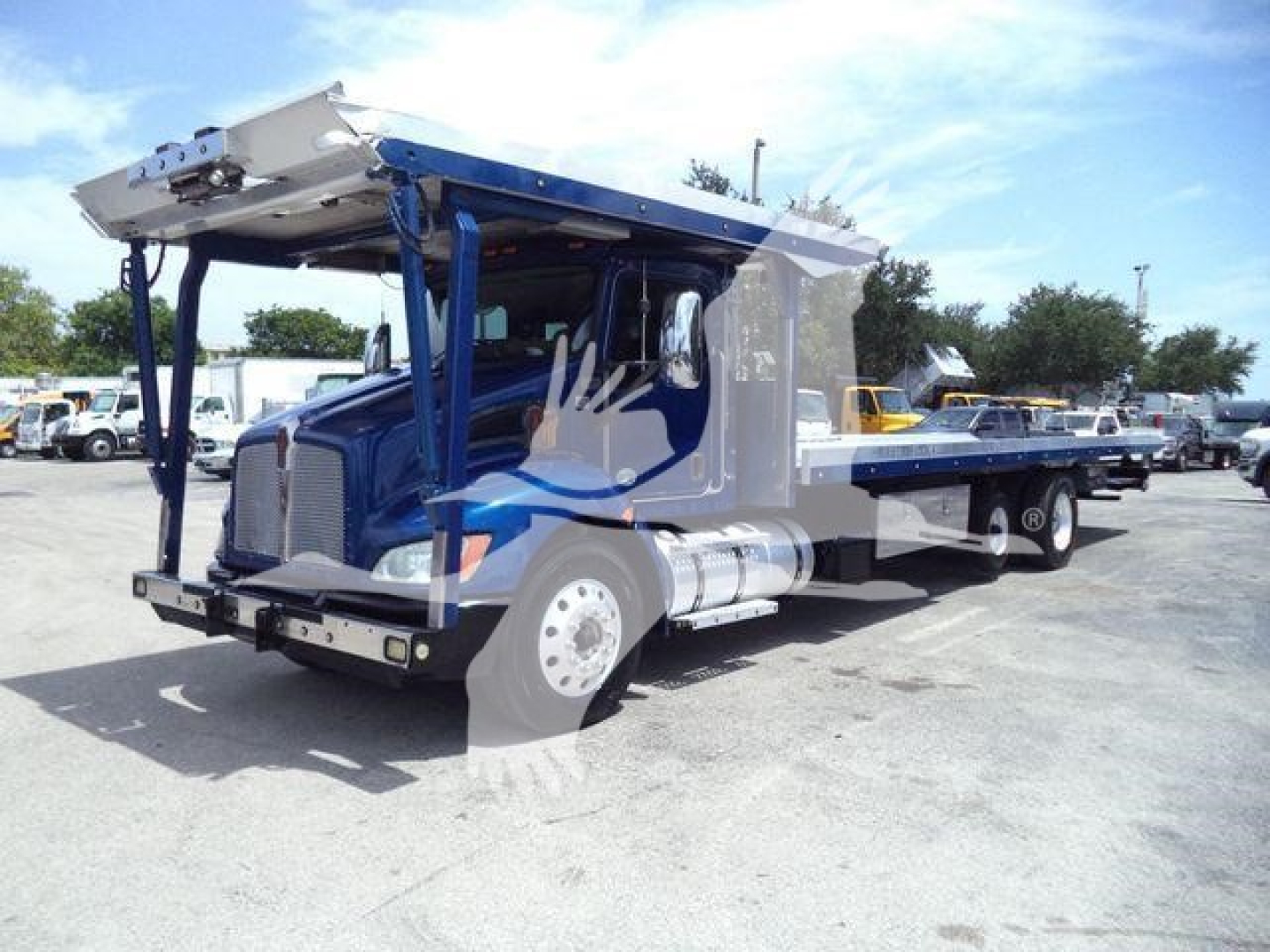 Kenworth T370 rollback tow truck in blue with hydraulic bed raised, side view showing cab and long wheelbase, 2016 model year.