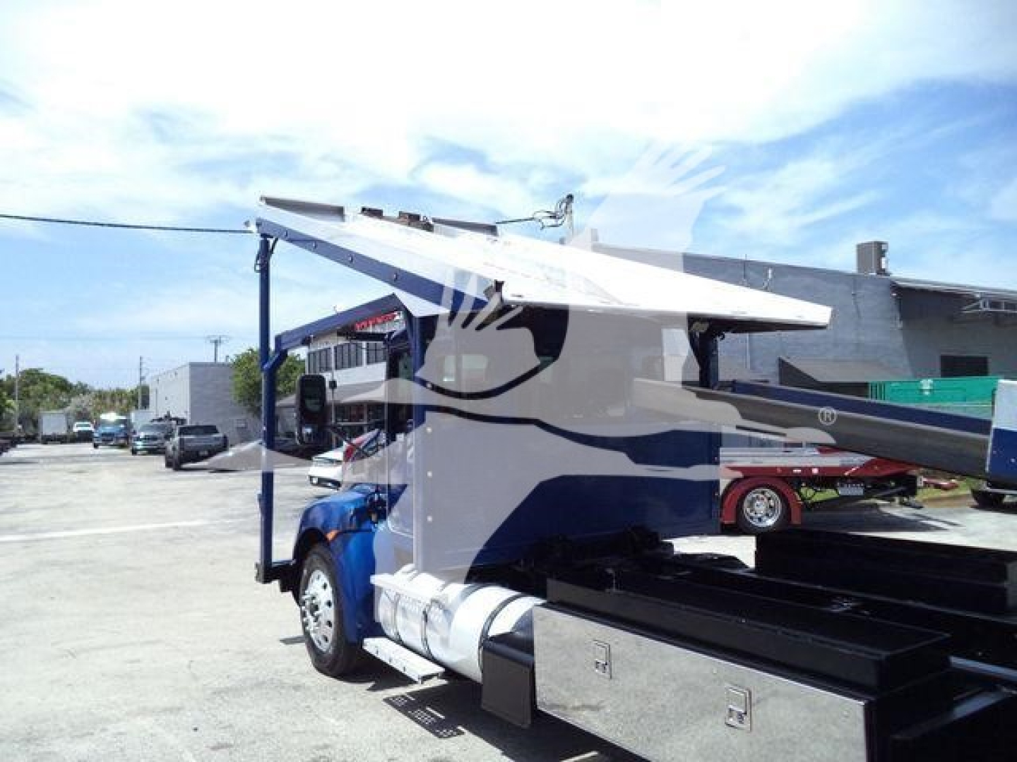 Kenworth truck towing rollback wrecker equipment showing hydraulic boom and side storage boxes.