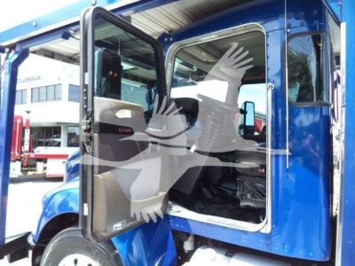 Kenworth T370 cab with open door showing interior Passenger seat and dashboard; blue exterior; rolling rollback truck in background