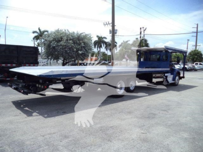 Kenworth T370 rollback tow truck with flatbed chassis and blue cab, side view showing long trailer bed and multiple axles.