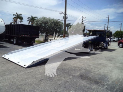 Kenworth T370 rollback truck with an extended flatbed ramp in a parking lot, side view showing the metal ramp unfolded.