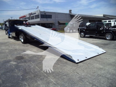 Kenworth T370 rollback tow truck with a lowered front ramp, metal deck and towing equipment in a dealership lot