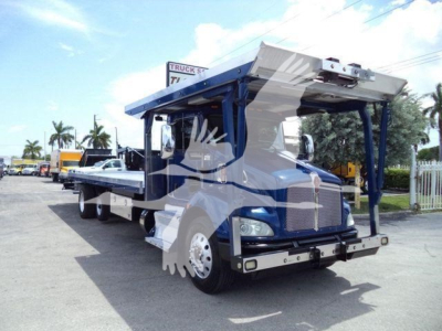 Kenworth T370 rollback truck shown from front-left angle with crane raised, blue cab and chrome bumper, daytime.