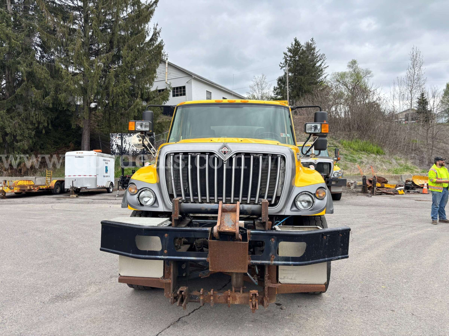 Front view of a yellow 2007 Sterling L8500 dump truck with a heavy grille, snow plow mount, and rusted receiver; visible text on the truck includes Sterling chrome grille and orange warning lights.