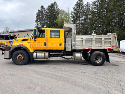 Dump truck showing side view of a yellow 2007 Sterling L8500 with a gray dump bed and dual rear wheels.