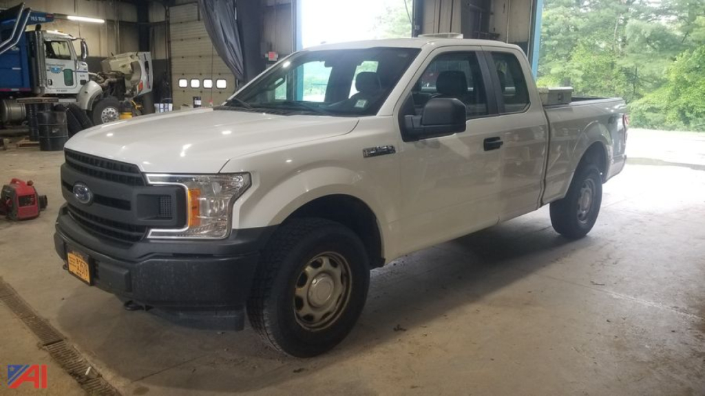 Front-left view of a white 2016 Ford F-150 pickup truck with extended cab in a workshop. visible text on badge and side mirror. 