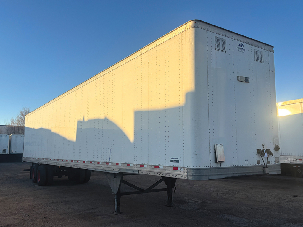 Trailer showing a white Hyundai aluminum box trailer with dual rear doors and reflective safety stripe along lower edge.
