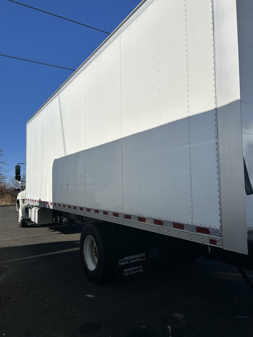 Truck body side of a 2015 Hino 338 box van showing white cargo trailer with reflective stripe