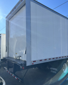 Box van truck rear showing white cargo box with framed steel rails and back ramp, Hino 338 listing context not visible text on image