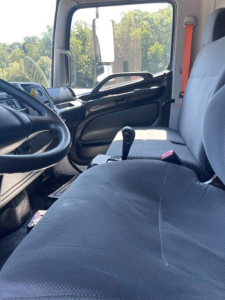 Cab interior of a 2015 Hino 338 truck showing driver seat and passenger bench with steering wheel and gear shifter.
