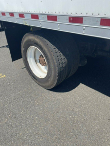 Hino 338 truck rear wheel and cargo box showing dual rear tires and side panel.