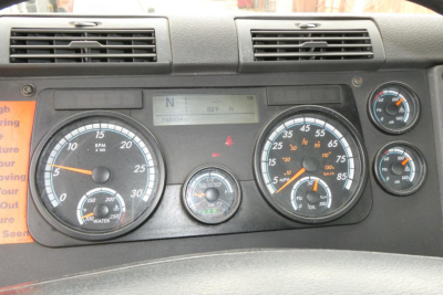 Dashboard of a Freightliner Cascadia 125 showing multiple gauges incl. RPM, speedometer, fuel, air pressure, and digital display.