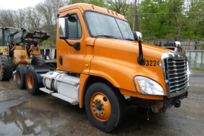 Orange Freightliner Cascadia 125 daycab truck in side view showing front grille and cab numbers