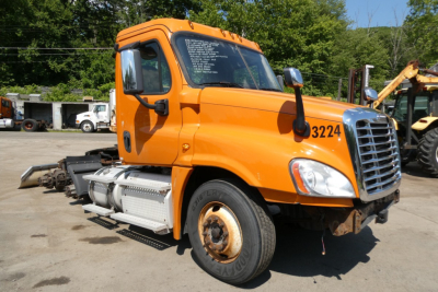 Orange Freightliner Cascadia 125 daycab truck side view showing cab, wheel, and fuel tank with stock number 3224 and VIN on windshield.