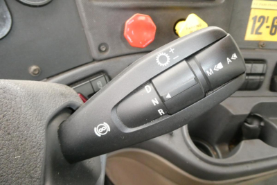 Tractor truck gear selector stalk with shift positions P R N D and manual +/-, dashboard buttons and a red knob in view.
