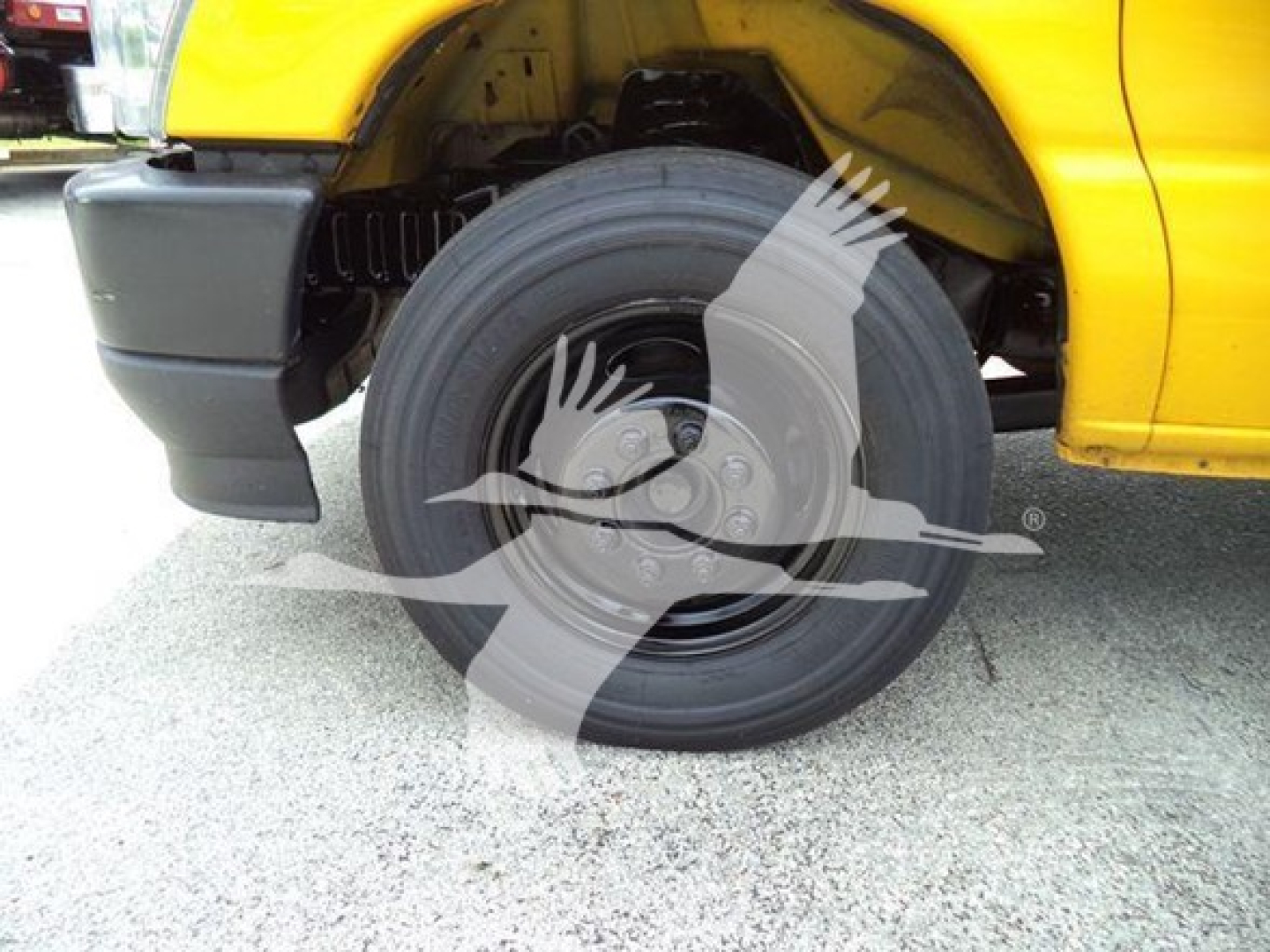 Ford E-350 cutaway van wheel well showing front tire and yellow body paint.
