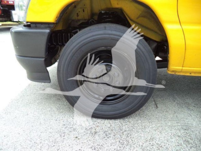 Ford E-350 cutaway van wheel well showing front tire and yellow body paint.