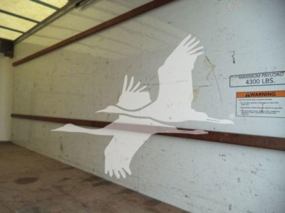 Truck trailer interior side with stenciled seagull graphic and warning label reading 'MAXIMUM PAYLOAD 4300 LBS' on the wall.