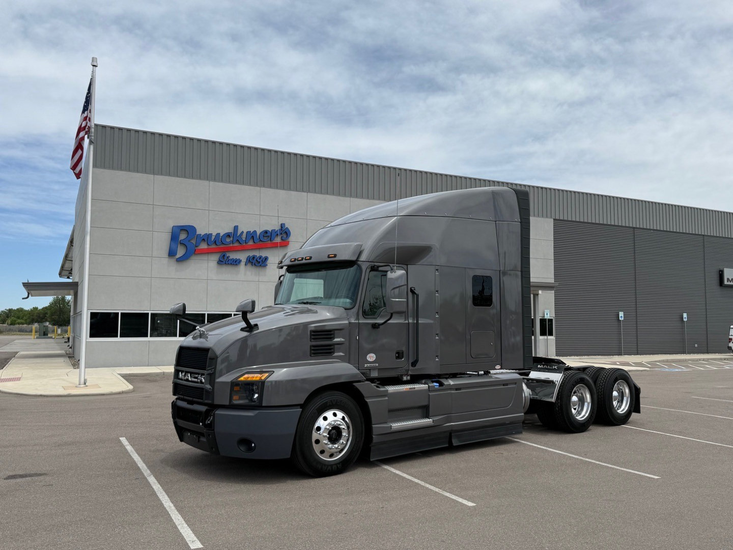 Truck cab in 2024 Mack Anthem sleeper tractor in front of a dealership building with Brackett's Auto Deal sign