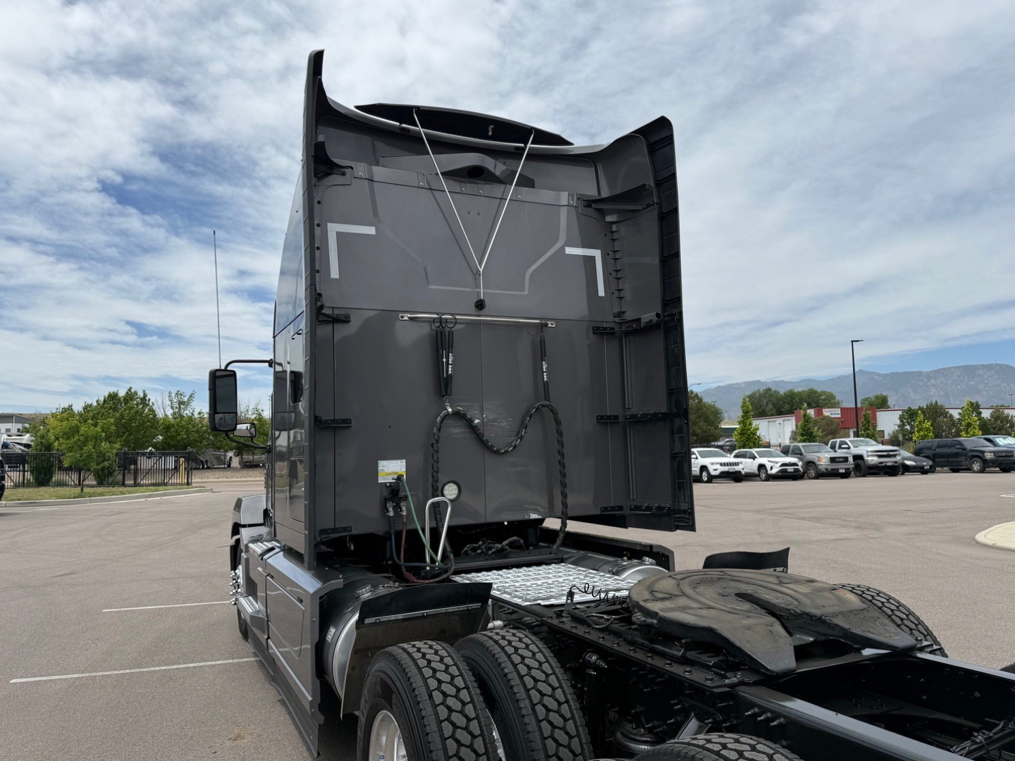 Truck tractor rear view showing fifth wheel area and back of sleeper with hoses and electrical lines connected.