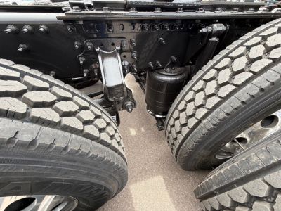 View under a 2024 Mack Anthem showing dual rear axles with heavy-duty tires and suspension components.