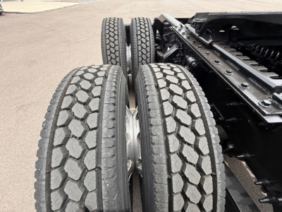 Twin rear axles and tires of a Mack Anthem truck chassis showing dual tires with hexagonal tread, metal frame, and connectors.